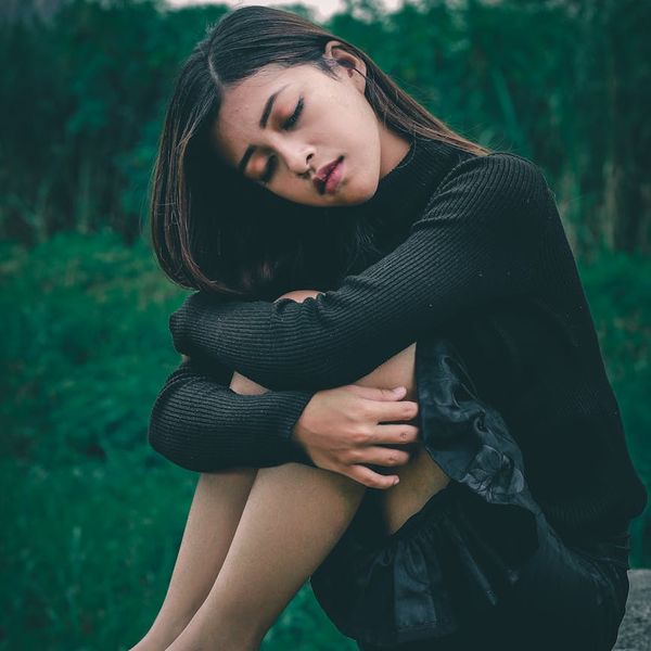 Person sitting in a calm meditation pose in a serene setting.